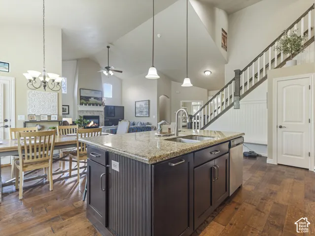 Kitchen island featuring stone countertops, integrated stainless steel sink, and dark cabinetry