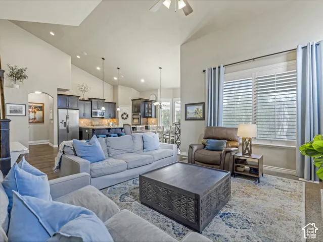 Open-concept interior featuring vaulted ceilings, recessed lighting, wood-finish flooring, and large windows with horizontal blinds