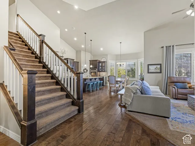 Open concept interior featuring vaulted ceilings, wood-finish flooring, staircase with stained wood handrails and painted balusters, recessed lighting, and a bay window