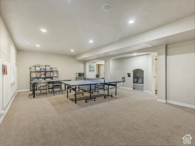 Finished interior space featuring neutral wall tones, recessed lighting, carpeted flooring, architectural archways, and a built-in recessed nook