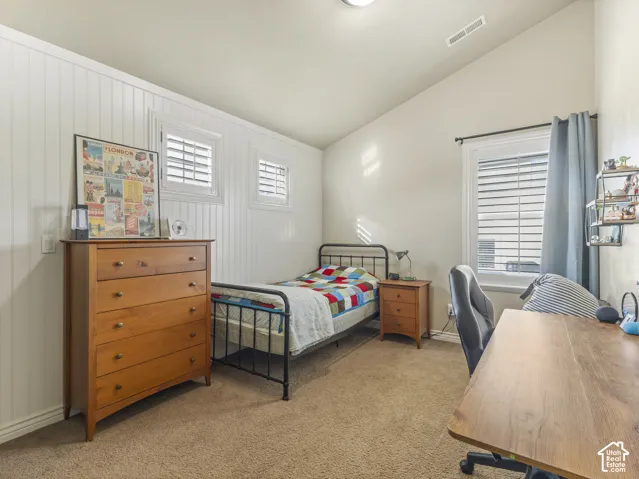 Vaulted ceiling, beadboard wainscoting, and windows featuring plantation-style shutters