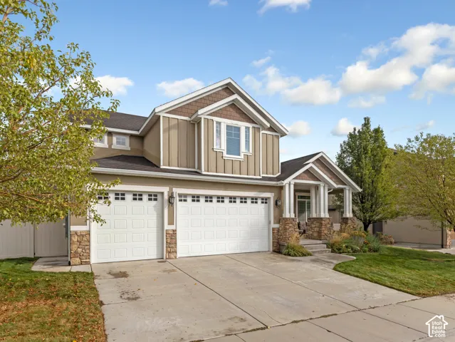 Multi-level exterior featuring vertical siding, stone veneer accents, a concrete driveway, a three-car garage, and a covered front porch with decorative columns