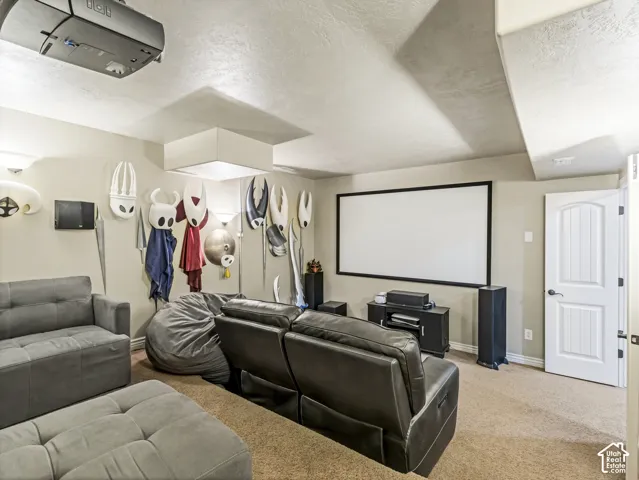 Media room featuring a ceiling-mounted projector, wall-mounted projection screen, tiered floor levels, and a white paneled door