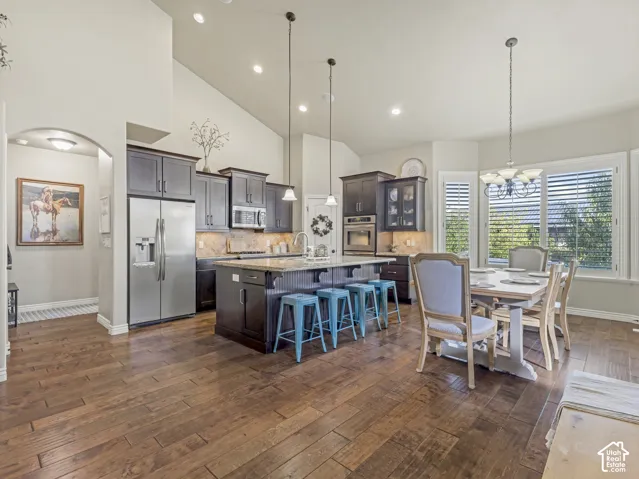 Vaulted ceilings, wood-finish flooring, dark-toned cabinetry, stone-surface kitchen island, and built-in stainless steel double wall oven