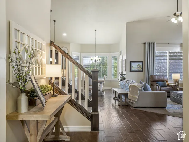 Interior featuring wood-finish flooring, vaulted ceilings, a staircase with a wooden handrail, and a bay window