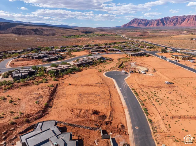 Newly developed cul-de-sac with paved road, surrounded by existing residential structures and red rock landscape