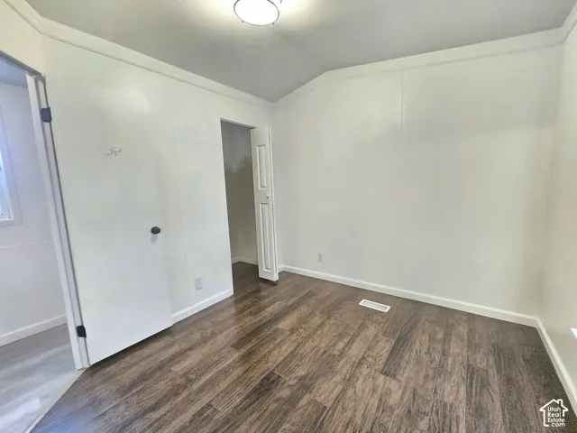 Room featuring wood-finish flooring, crown molding, and a flush-mount ceiling light fixture