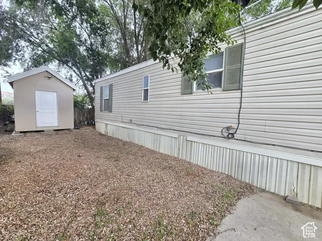 Exterior featuring horizontal vinyl siding, green window shutters, a detached storage shed, and a gravel-surfaced ground area