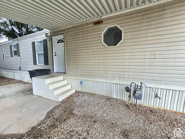 Exterior featuring horizontal vinyl siding, an attached metal carport, concrete stairs, and a distinctive octagonal window