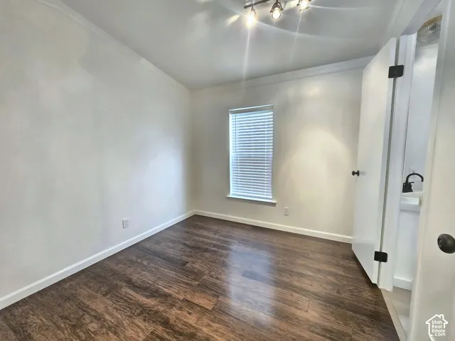 Room featuring wood-finish flooring, neutral wall paint, a window with horizontal blinds, and multi-bulb track lighting