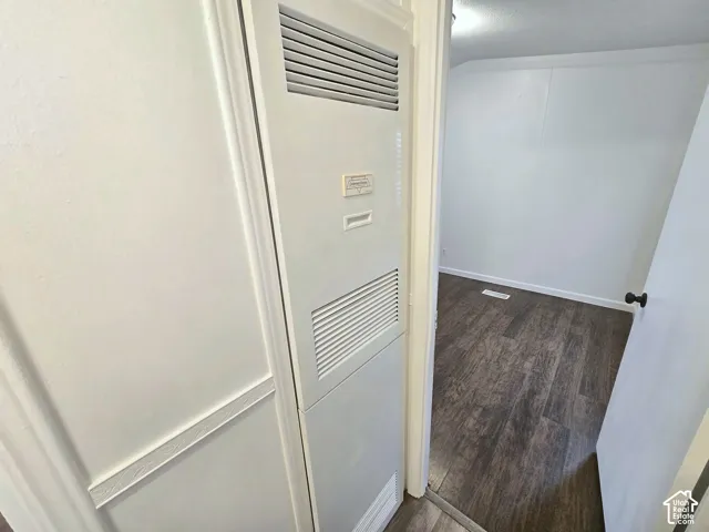 Built-in vertical utility access panel with dual louvered ventilation and wood-finish flooring