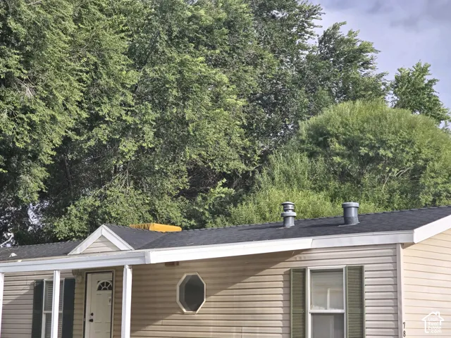 Beige vinyl siding, asphalt shingle roofing, decorative octagonal window, and shutters