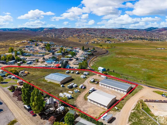 Expansive acreage featuring three large metal-siding storage structures and dedicated dirt-surfaced drive areas