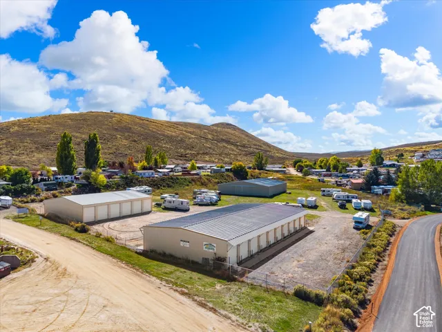 Multiple steel-frame storage buildings featuring metal roofs, reinforced roll-up doors, and gated perimeter fencing set against a mountain backdrop