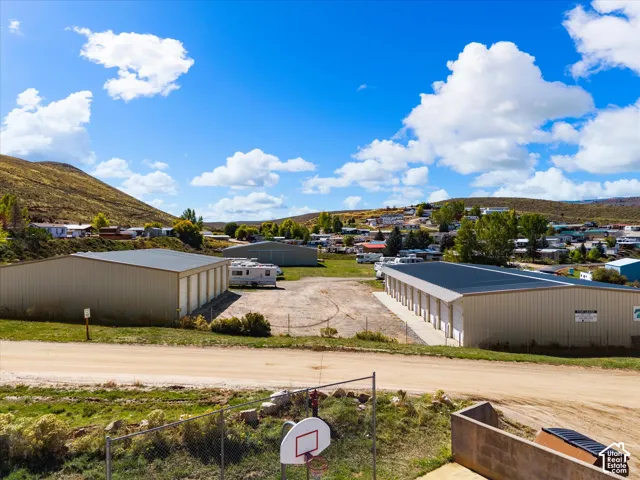 Expansive lot featuring multiple metal storage structures, roll-up bay doors, a fenced perimeter, and mountain terrain backdrop