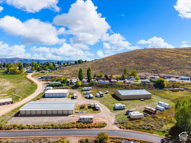Expansive acreage featuring multiple large-scale metal-sided storage structures, gravel driveways, and natural terrain