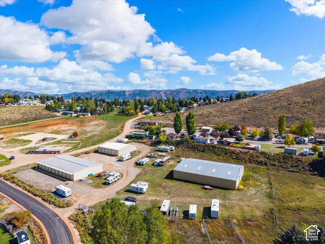 Expansive property featuring two large metal-sided workshop structures, gravel-surfaced driveways, open acreage, and a prominent mountain backdrop