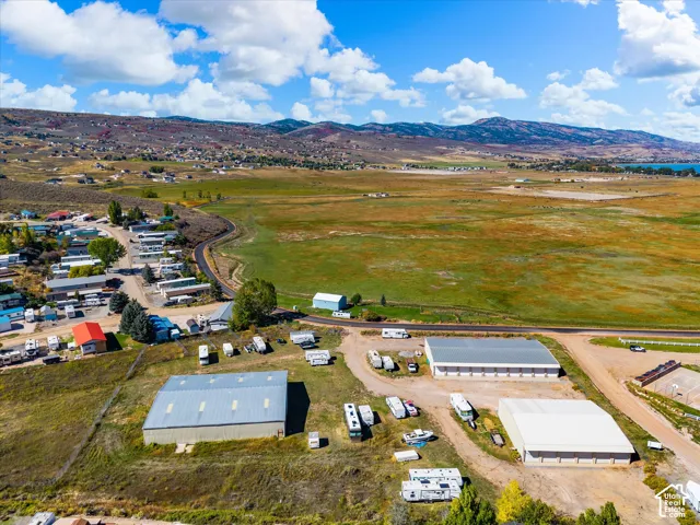 Aerial perspective of a sprawling property featuring multiple large-scale metal storage structures, expansive unpaved open-air parking areas, and mountainous topography