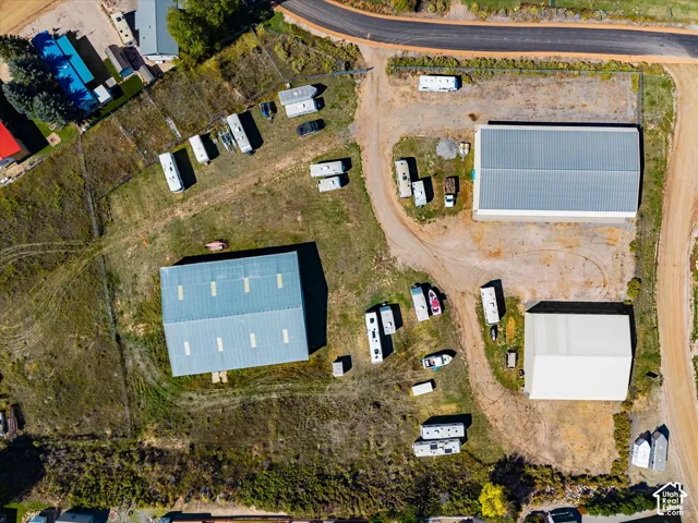Expansive parcel featuring three detached industrial-style buildings, unpaved driveway access, and perimeter fencing