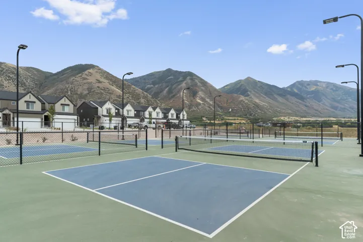Multiple sport courts featuring chain-link fencing, LED lighting fixtures, and a mountain backdrop