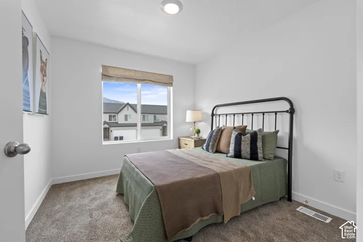 Neutral-toned carpeting, crisp white walls, flush-mount ceiling lighting, and a window with a fabric roman shade