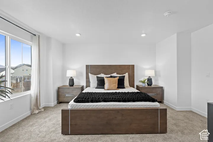 Neutral-toned wall-to-wall carpeting, recessed ceiling lighting, and large window with exterior exposure