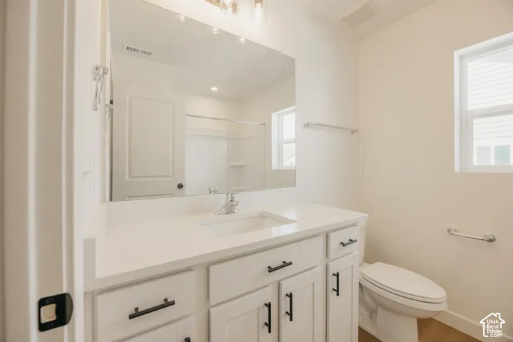 White vanity with a quartz countertop, integrated rectangular sink, matte black hardware, and an expansive wall-mounted mirror