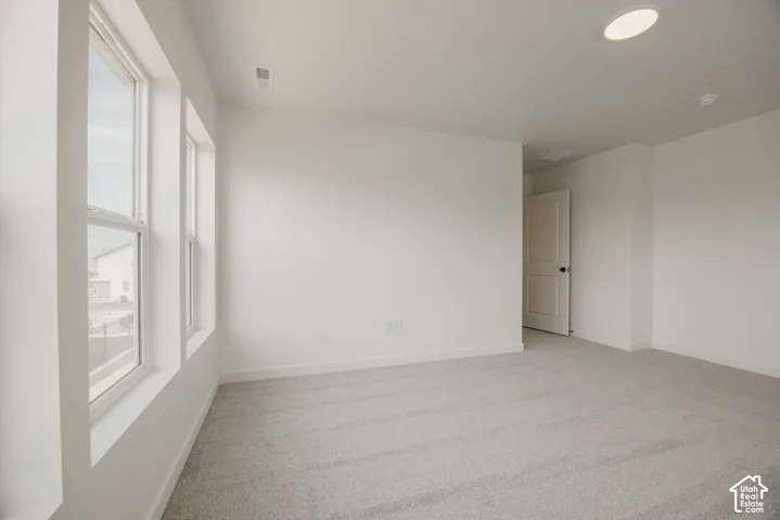 Neutral-toned carpeting, large windows, recessed lighting, and a paneled interior door
