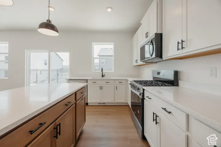 Kitchen featuring white shaker-style cabinetry, quartz countertops, a center island with a wood-finish base, stainless steel gas range, and recessed lighting