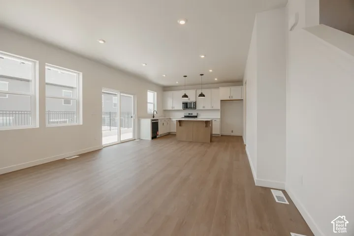 Open-concept kitchen featuring white shaker-style cabinetry, wood-finish kitchen island, recessed lighting, and wood-finish flooring
