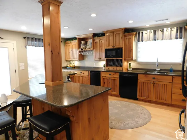 Kitchen featuring custom wood cabinetry, a central island with an integrated support pillar, recessed lighting, and stone-finish countertops