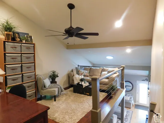 Vaulted ceilings, skylight, cable railing system, dark wood-finish flooring, and multi-blade ceiling fan