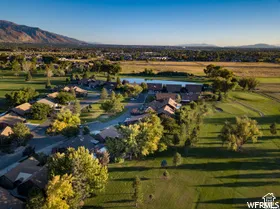 Aerial perspective featuring expansive green space, mature trees, a water feature, and mountain topography