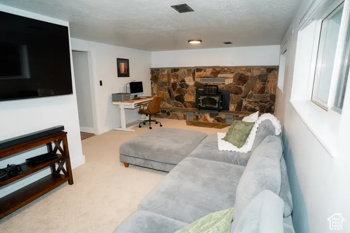 Floor-to-ceiling natural stone wall featuring a built-in wood-burning stove, wall-to-wall carpeting, and recessed ceiling lighting