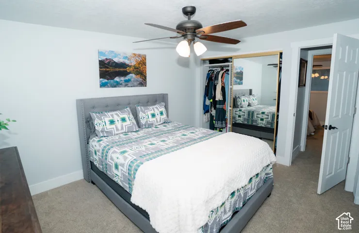 Neutral wall tones, carpeted flooring, ceiling fan with light kit, and closet with sliding mirrored doors