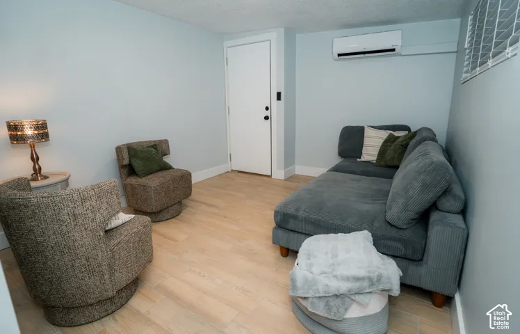 Room featuring wood-finish flooring, a wall-mounted ductless mini-split air conditioning unit, and a white single-panel door