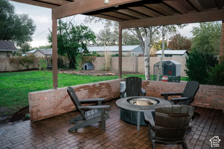 Covered brick patio featuring a herringbone-patterned brick floor, a low-profile perimeter brick wall, and a wood-beam pergola overhead