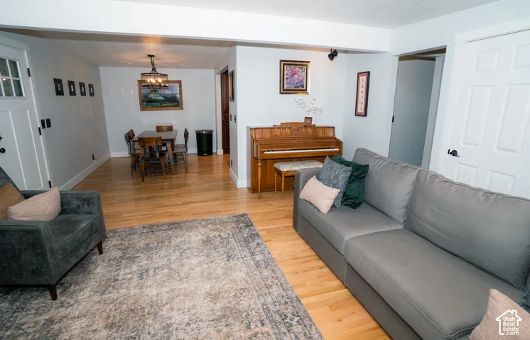 Light-toned wood-finish flooring, multi-pane glass entry door, and decorative multi-bulb chandelier
