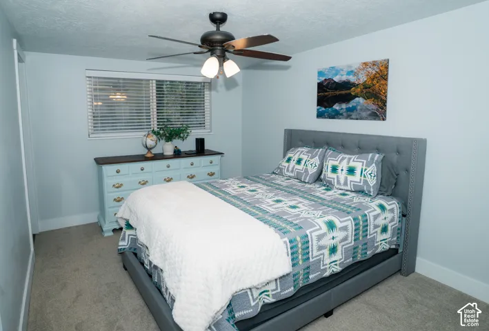 Bedroom featuring carpeted flooring, neutral wall paint, and a ceiling-mounted fan with integrated light fixtures