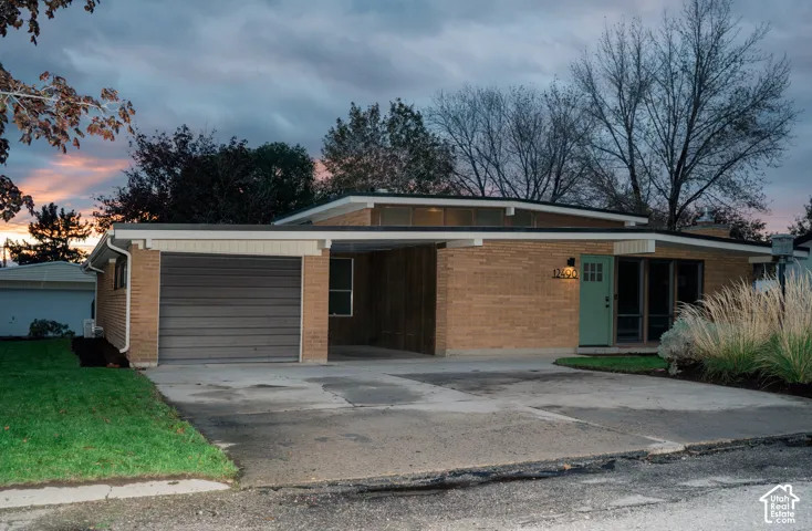 Mid-century modern exterior featuring a low-slung roofline, expansive masonry facade, integrated carport, and clerestory windows