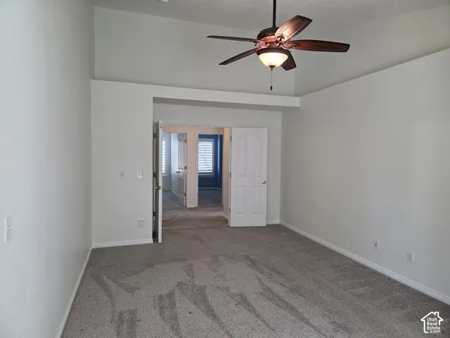 Room featuring a vaulted ceiling, ceiling fan with integrated lighting, wall-to-wall carpeting, and double doors