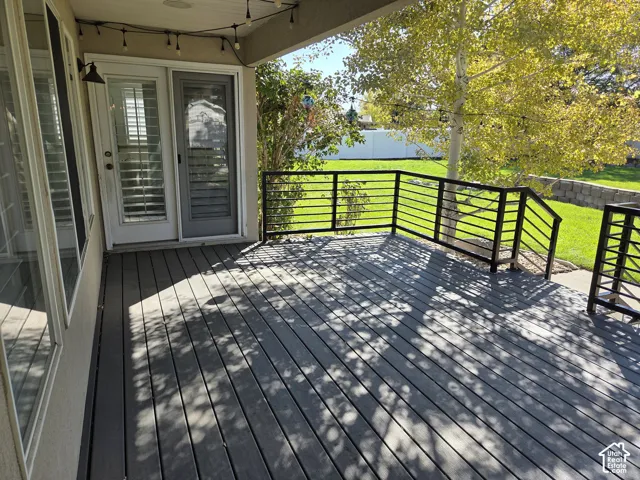 Composite deck featuring horizontal black metal railing, stairs to the yard, and a covered entry with a glass-panel exterior door