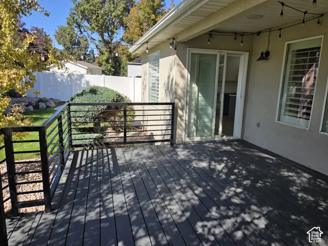 Composite deck featuring a matte black metal railing, sliding glass doors, and recessed exterior lighting