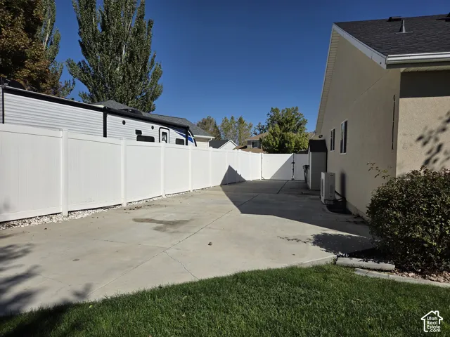 Concrete side parking pad enclosed by white vinyl privacy fencing