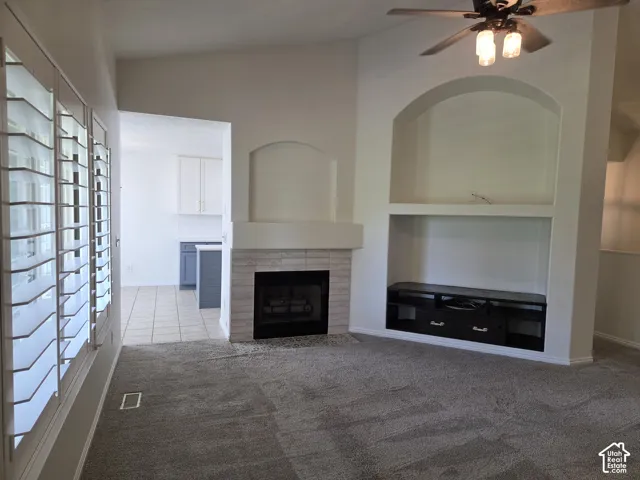 Vaulted ceilings, fireplace with light-toned masonry surround, built-in recessed shelving, and plantation shutters