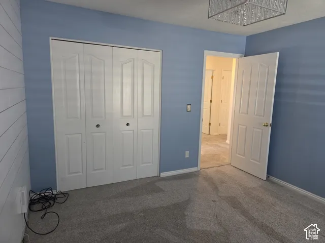 Interior space featuring horizontal plank wall detailing, carpeted flooring, a four-panel bi-fold closet, and a decorative ceiling fixture