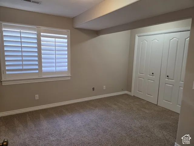 Room featuring neutral-toned carpeting, plantation shutters, and dual-panel closet doors