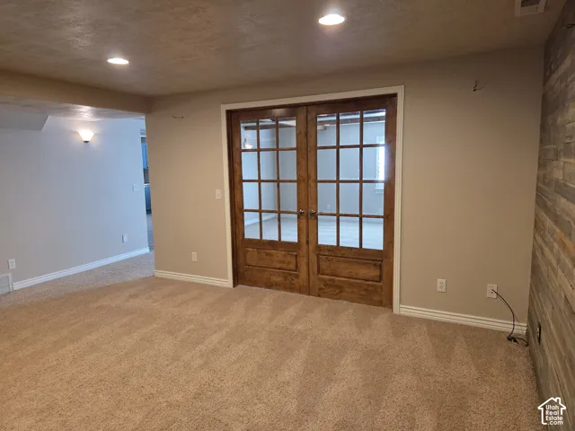 Interior space featuring wood-frame French doors, recessed lighting, and a textured wood-panel accent wall