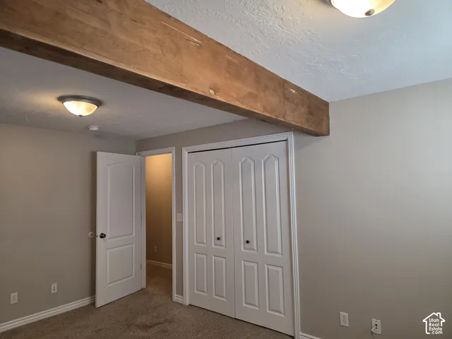 Exposed natural wood beam, flush-mount ceiling lighting, and white six-panel interior doors