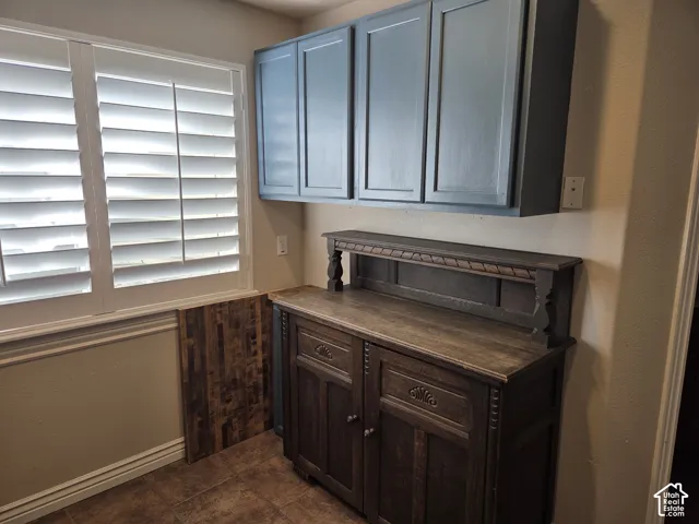 Wall-mounted matte blue cabinetry, dark-stained wood built-in hutch with decorative carving, and interior window shutters